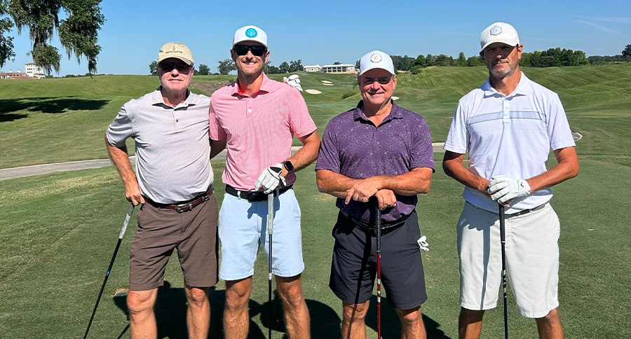 Four golfers pose on the championship golf course during a member tournament at The Club at Iron Lake.
