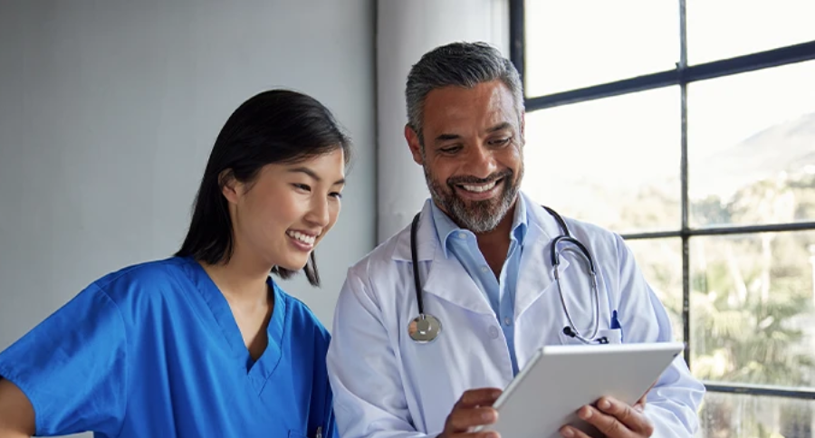 Doctor and healthcare professional reviewing information together on a tablet.