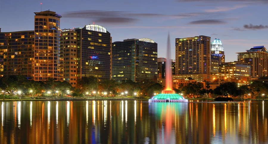 Orlando skyline and Lake Eola fountain illuminated at dusk in Central Florida.